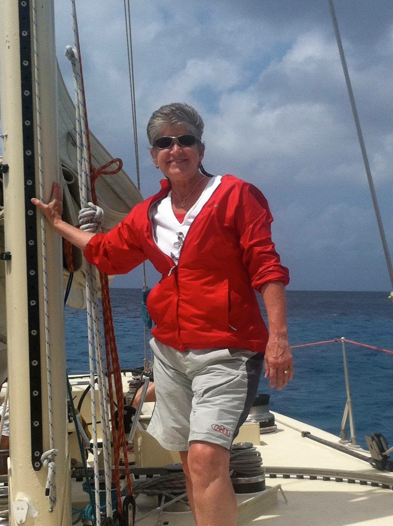 Instructors Captain Marcia Baker aboard a sailboat with open blue water behind her